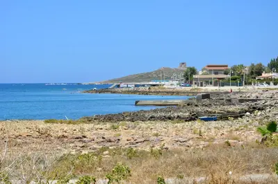 a beach with the ocean and houses in the background at La Casetta di Ale in Isola delle Femmine