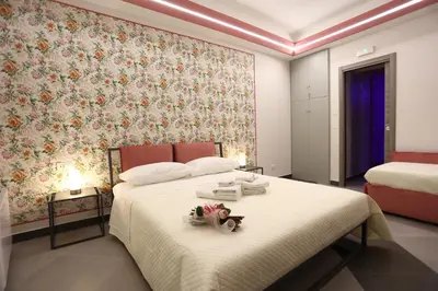 a bedroom with a white bed with a floral wallpaper at De Spuches House in Caccamo