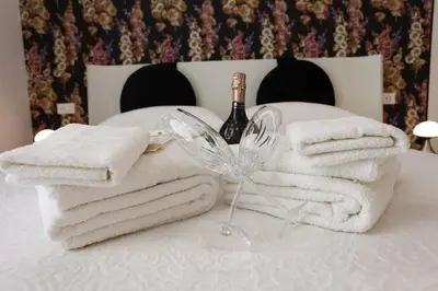 a pile of towels and a bottle of wine on a bed at De Spuches House in Caccamo