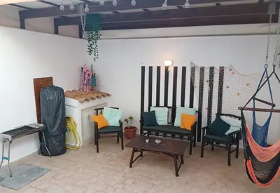 a room with chairs and a hammock and a table at Casa Joe in San Vito lo Capo