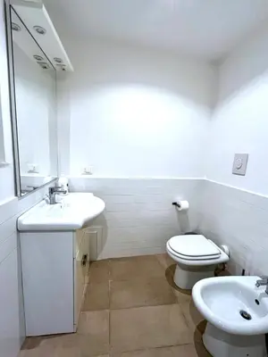 a white bathroom with a toilet and a sink at Casetta Bontà in Palermo