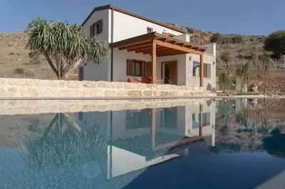 a house with a reflection in a pool of water at Villa Eos con piscina privata in Scopello