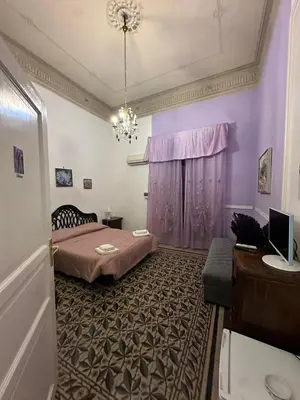 a bedroom with a bed with purple walls and a chandelier at B&B Salinas in Palermo