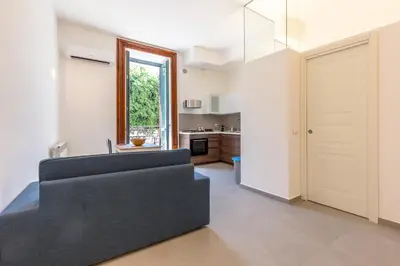 a living room with a black couch and a kitchen at Loft Piazza Marina By DomuSicily in Palermo