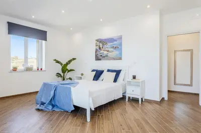 a white bedroom with a white bed and blue pillows at Old Port Luxury Apartments in Palermo