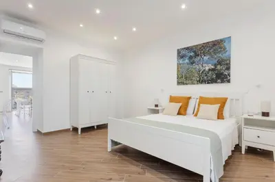 a white bedroom with a bed with orange pillows at Old Port Luxury Apartments in Palermo