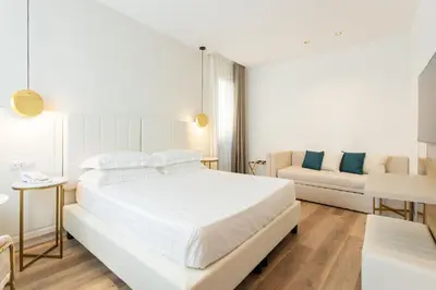 a white bedroom with a bed and a couch at Mondello Glam Hotel & Terrace in Mondello