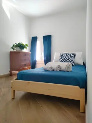 a bedroom with a bed with blue sheets and a dresser at Liberty Blue House in Palermo