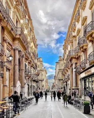 a group of people walking down a street between buildings at Casa Verdura in Palermo