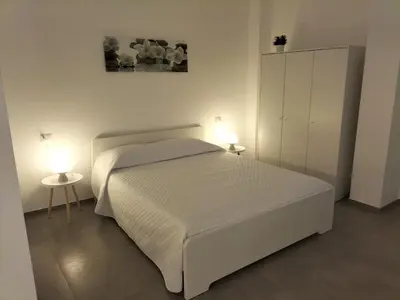 a white bedroom with a bed and two lamps at Casa vacanze LoRiLù in Castellammare del Golfo
