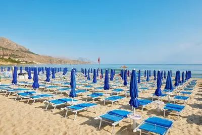 a group of blue chairs and umbrellas on a beach at Casa vacanze LoRiLù in Castellammare del Golfo