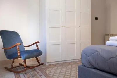 a blue rocking chair sitting next to a bed at Sella Apartment Centro Storico in Palermo
