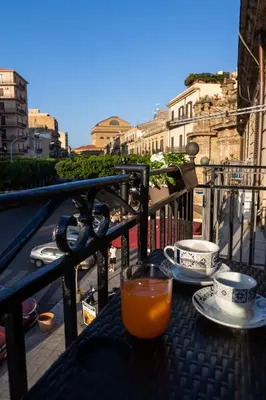 a table with a glass of orange juice on a balcony at Ai Mercati di Palermo in Palermo