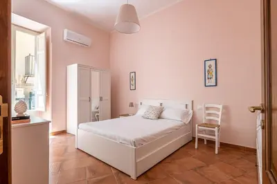 a bedroom with a white bed and a chair at Il Cortile degli Aragonesi by Wonderful Italy in Palermo