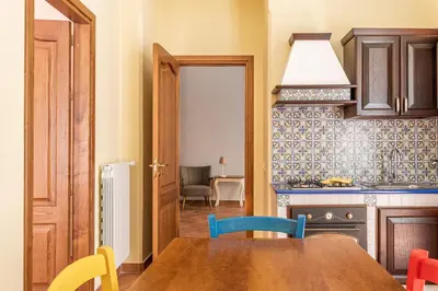 a kitchen with a wooden table and colorful chairs at Il Cortile degli Aragonesi by Wonderful Italy in Palermo