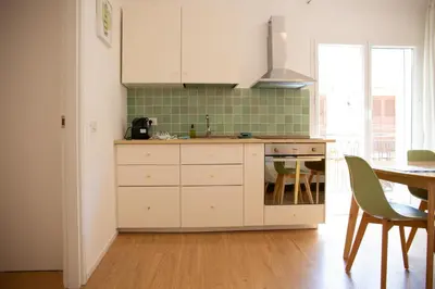 a kitchen with white cabinets and a table at Solemar Sicilia - Casa Minerva in Santa Flavia