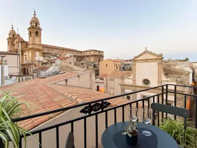 a balcony with a table and wine glasses at Lùlom - Rooftop Boutique Rooms in Palermo