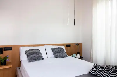 a bedroom with a white bed with two pillows at Lùlom - Rooftop Boutique Rooms in Palermo