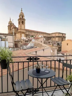 a table and chairs on a balcony with a view of a city at Lùlom - Rooftop Boutique Rooms in Palermo