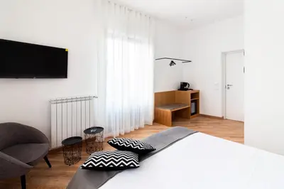 a white bedroom with a bed and a chair at Lùlom - Rooftop Boutique Rooms in Palermo