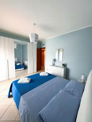 a blue bedroom with a large bed and a bathroom at Appartamento Trinacria in Castellammare del Golfo
