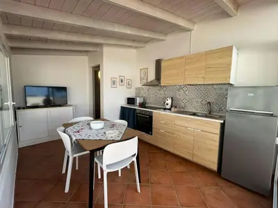 a kitchen with a table and chairs and a refrigerator at Monte Luna - E-bikes incluse per raggiungere il centro e la spiaggia in 3 minuti in San Vito lo Capo