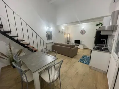 a kitchen and a living room with a table and chairs at Alloggio delle Carrozze al Ballarò in Palermo