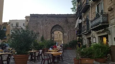 an outdoor patio with tables and chairs and an archway at Alloggio delle Carrozze al Ballarò in Palermo