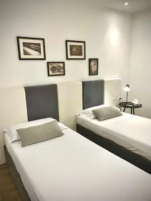 two beds in a hotel room with pictures on the wall at Normanni 5 Rooms & Apartment in Palermo