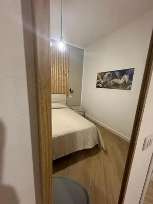 a white bedroom with a bed and a chair at casa consiglio ardicula in Terrasini