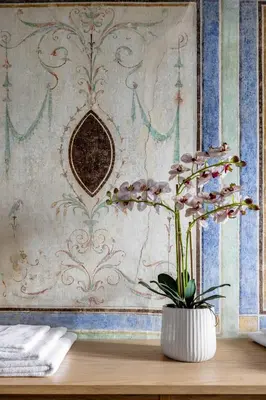 a vase with flowers on a table in front of a wall at Maruisa suite apartment in Palermo