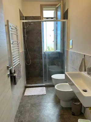 a bathroom with a shower and a toilet and a sink at Sunset Holiday House in Cefalù