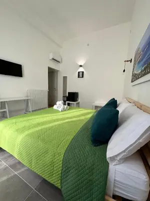 a bedroom with a green bed and a television at My Happy Place Rooms in Palermo