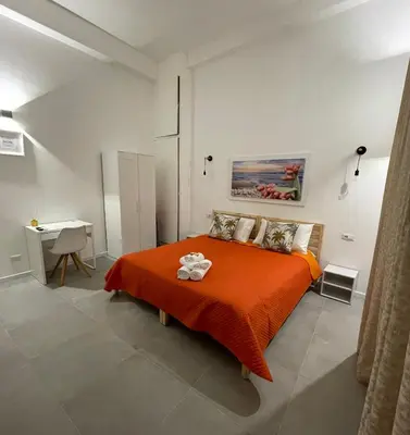 a bedroom with a bed with an orange blanket at My Happy Place Rooms in Palermo