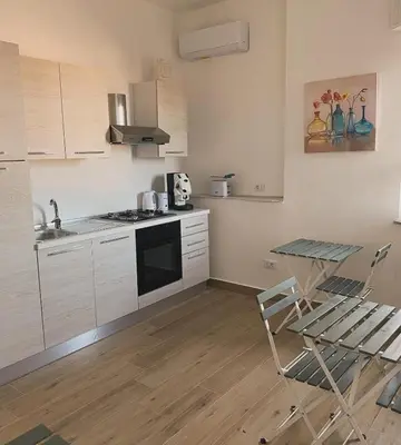 a kitchen with white cabinets and a table and a stove at Casa Margherita in Termini Imerese