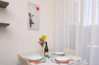 a table with plates and a vase of flowers on it at Anna's Central Apartment in Palermo