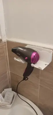 a black and pink blow dryer hanging from a wall at new suite in Palermo