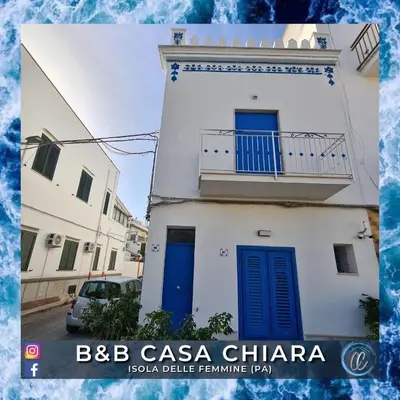 a white building with blue doors and a balcony at Casa Delle Femmine in Isola delle Femmine