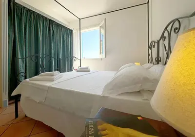 a bedroom with a large white bed with a window at Solemar Sicilia - Casa Eos in Porticello
