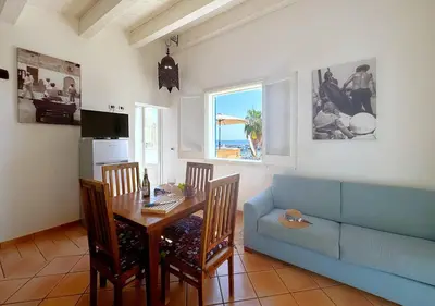 a living room with a table and a blue couch at Solemar Sicilia - Casa Eos in Porticello
