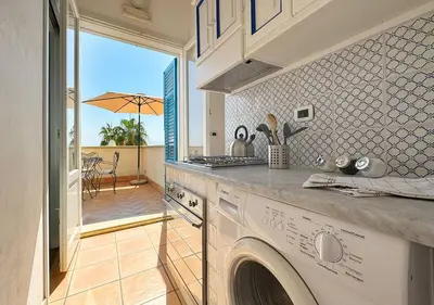 a kitchen with a washing machine and a patio at Solemar Sicilia - Casa Eos in Porticello