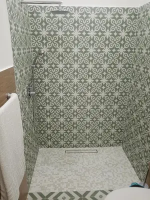 a bathroom with a shower with a patterned wall at Mediterranea casa vacanza in Capaci
