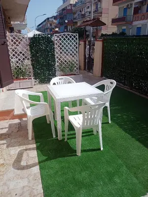 a white table and four chairs on a lawn at Mediterranea casa vacanza in Capaci