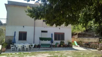 a white house with chairs and a table and a green tent at Casa Gelferraro in Calatafimi