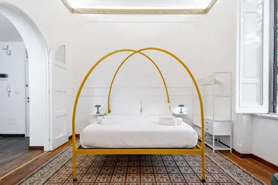 an arched bed in a white bedroom with a gold frame at Liberty Boutique Apartment in Palermo