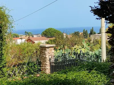 a black fence in a garden with the ocean in the background at Villa Sterlizia in Castellammare del Golfo