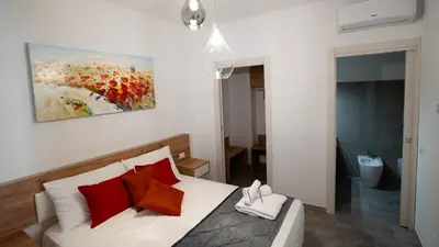 a bedroom with a bed with red pillows and a painting at Le Stanze del Duomo in Partinico