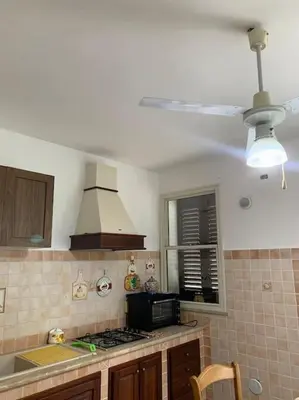 a kitchen with a stove and a ceiling fan at Loriano Apartment in Capaci