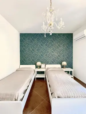 a bedroom with two beds and a chandelier at Loriano Apartment in Capaci