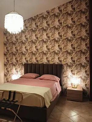 a bedroom with a large bed with a floral wallpaper at Dojo idro rooms in Carini